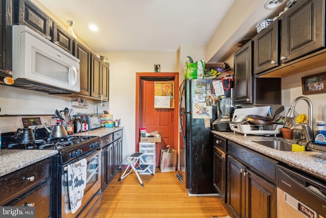 kitchen with white microwave, stainless steel gas range oven, a sink, dishwashing machine, and light wood-style floors