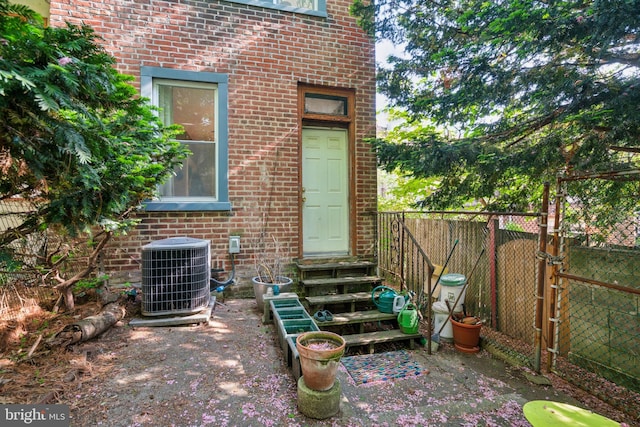 entrance to property with cooling unit, brick siding, and fence