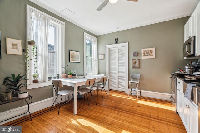 dining room featuring ornamental molding, baseboards, ceiling fan, light wood-style flooring, and a desk