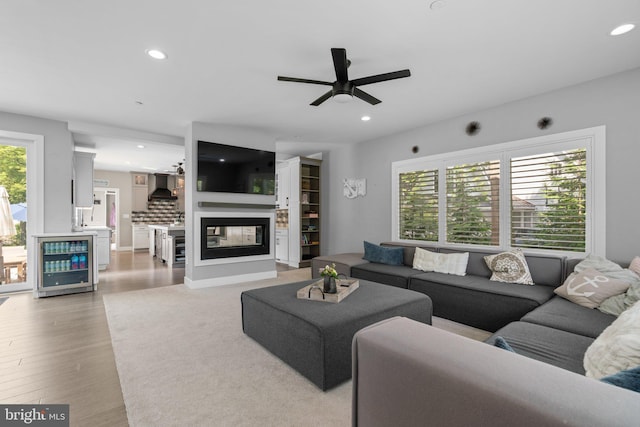 36 Boone Trl, Severna Park, MD 21146 - living room with wine cooler, a multi sided fireplace, ceiling fan, recessed lighting, and light wood-type flooring