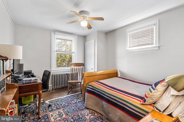 bedroom with radiator, wood finished floors, a desk, and a ceiling fan