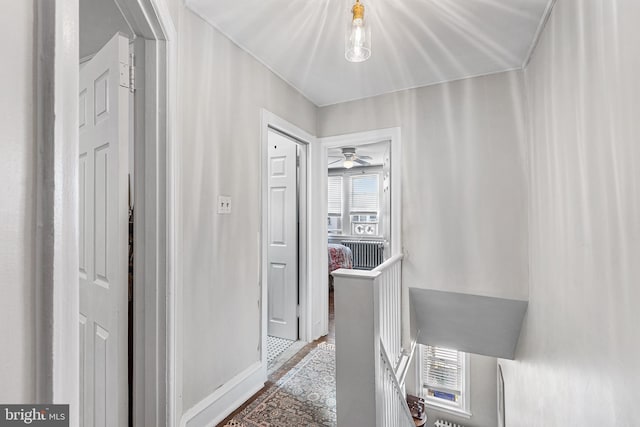 corridor featuring an upstairs landing, baseboards, and wood finished floors