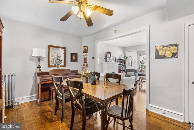 dining room featuring radiator heating unit, dark wood-style flooring, baseboards, and ceiling fan