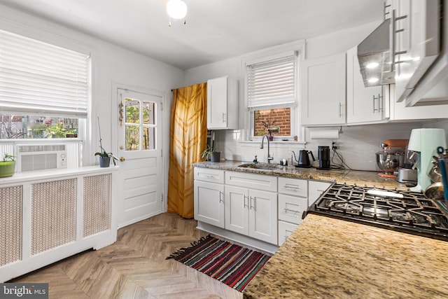 kitchen with a sink, white cabinetry, backsplash, and cooling unit