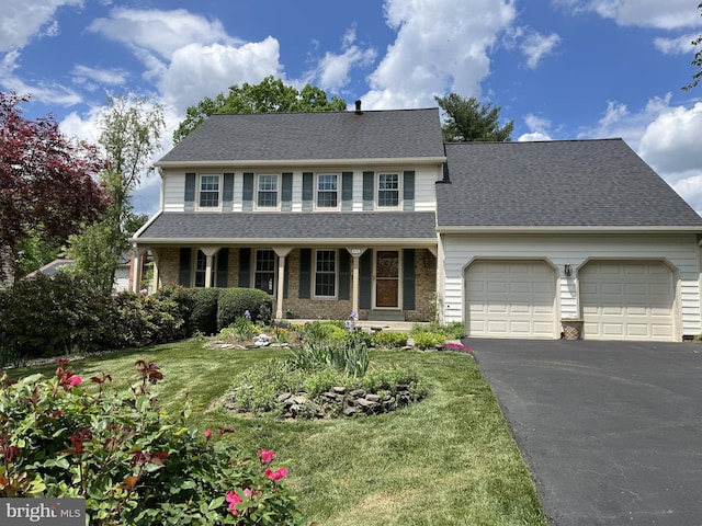 view of front facade with driveway, an attached garage, a front lawn, roof with shingles, and a porch