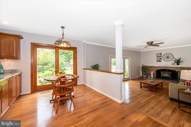 dining area featuring light wood-type flooring, baseboards, ceiling fan, crown molding, and decorative columns