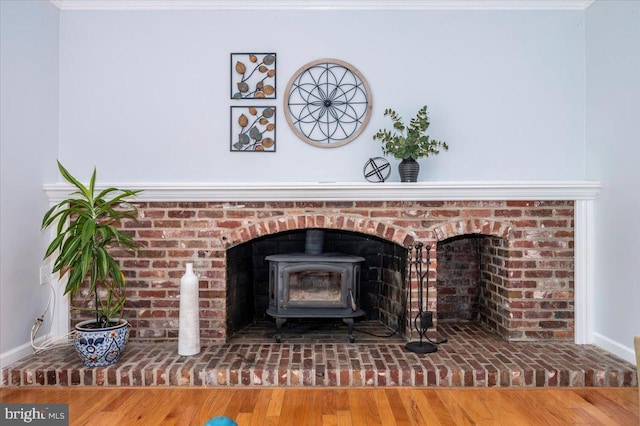 detailed view of a wood stove, baseboards, and wood finished floors