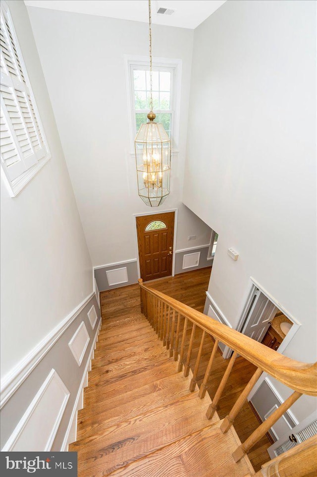 staircase with a chandelier and wood finished floors