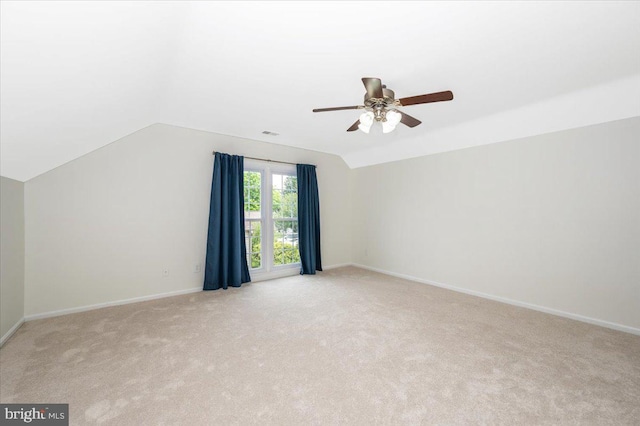 empty room with carpet flooring, lofted ceiling, ceiling fan, and baseboards
