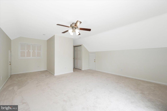 additional living space with light carpet, lofted ceiling, a ceiling fan, and baseboards