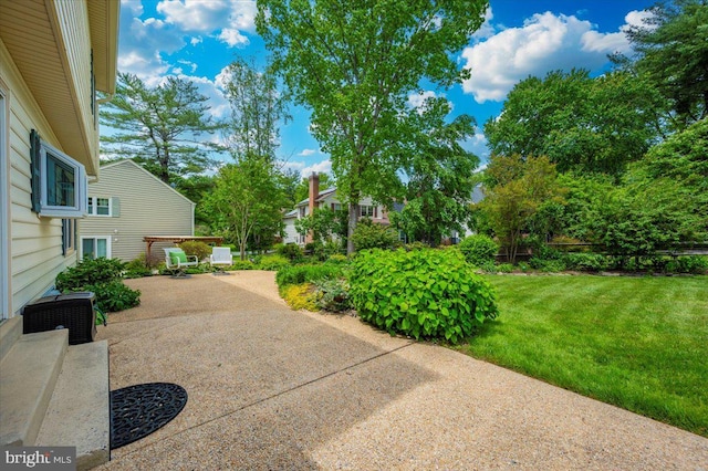 view of green lawn with a patio area
