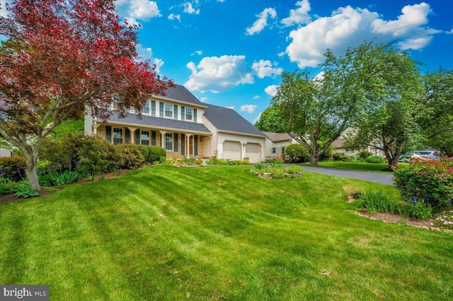 traditional-style house with an attached garage, driveway, and a front lawn