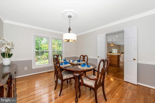dining room featuring light wood finished floors, ornamental molding, and baseboards