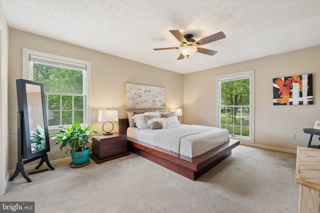 bedroom with multiple windows, carpet flooring, baseboards, and a textured ceiling