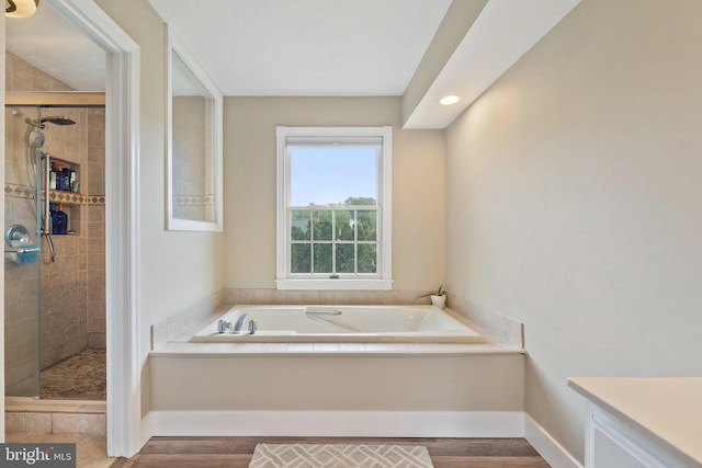 full bathroom featuring a garden tub, a stall shower, wood finished floors, baseboards, and recessed lighting