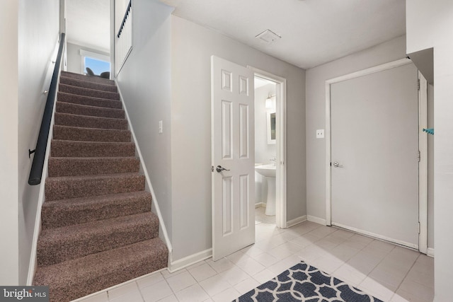 staircase featuring tile patterned floors and baseboards
