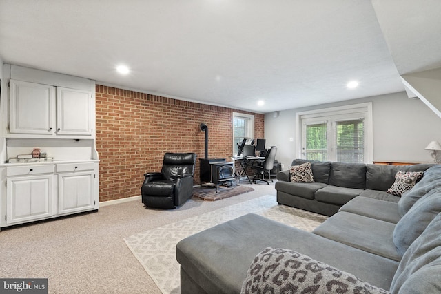 carpeted living area featuring brick wall, a wood stove, and recessed lighting