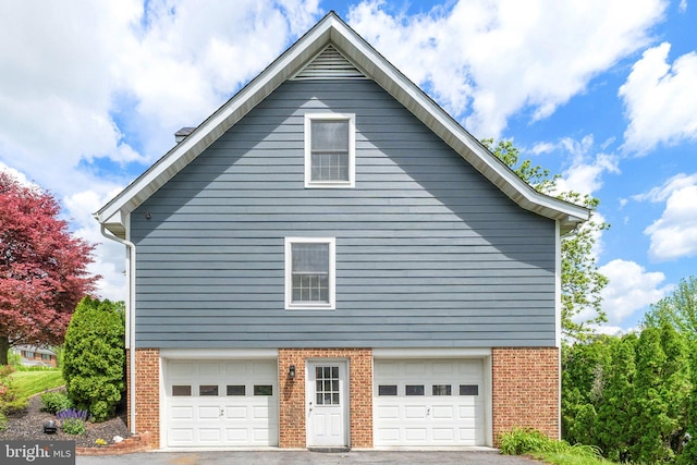 view of property exterior featuring brick siding, a garage, and driveway