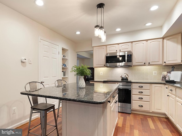5731 Wooden Spoon Ct, Burke, VA 22015 - kitchen featuring stainless steel appliances, a breakfast bar area, backsplash, a kitchen island, and light wood-style floors