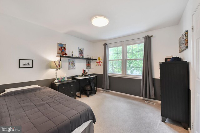 bedroom featuring light carpet and a desk