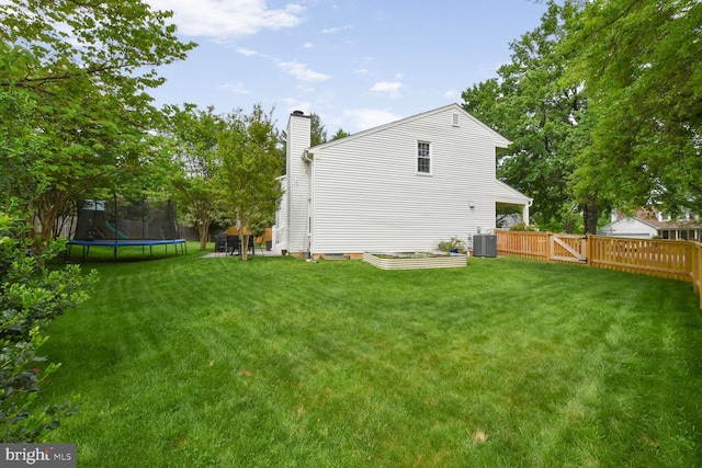 back of property with a trampoline, a chimney, and central air condition unit
