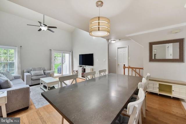 dining space with wood finished floors, ceiling fan, and vaulted ceiling