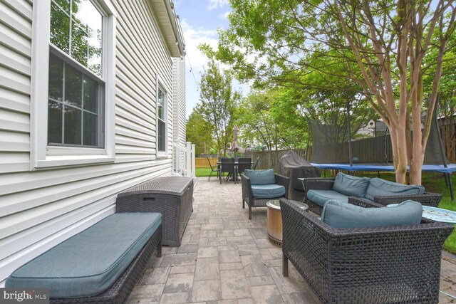 view of patio featuring a trampoline, a fenced backyard, and outdoor dining area
