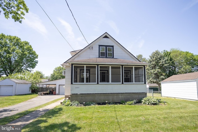 view of front of house with an outbuilding, a sunroom, a front lawn, and a garage