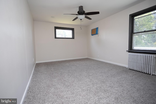 carpeted spare room with radiator heating unit, a ceiling fan, and baseboards