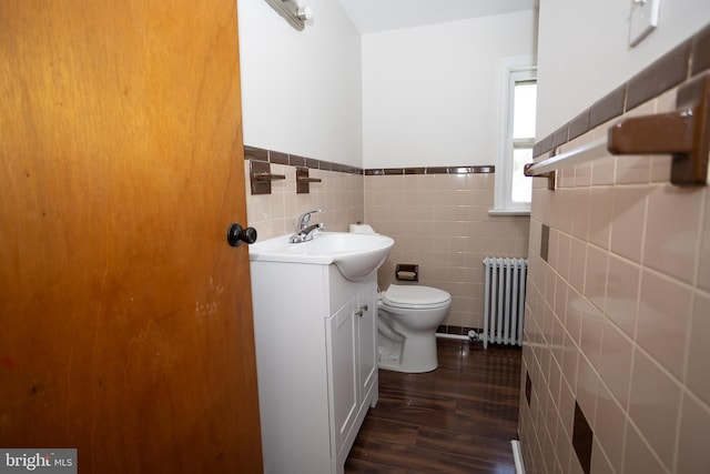 half bath featuring radiator, toilet, a wainscoted wall, tile walls, and vanity
