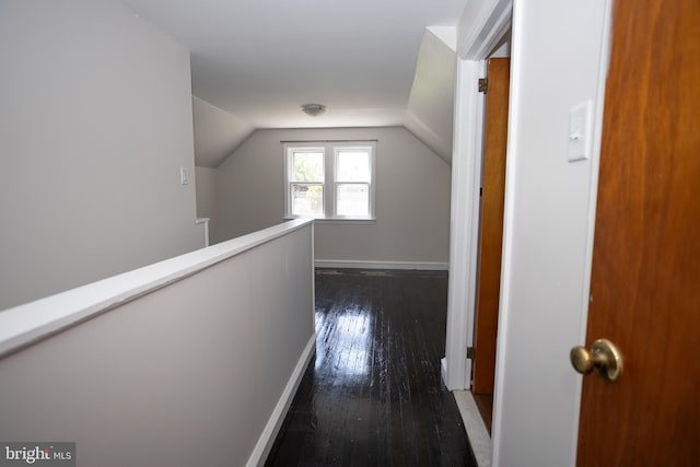 hallway featuring dark wood finished floors, lofted ceiling, an upstairs landing, and baseboards