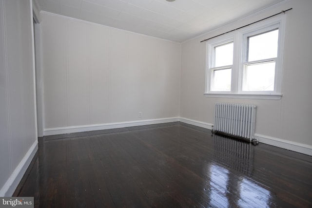 spare room with radiator, hardwood / wood-style floors, crown molding, and baseboards