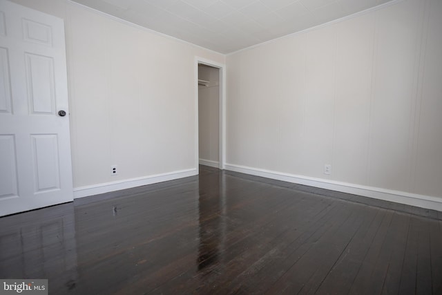 empty room featuring crown molding, hardwood / wood-style floors, and baseboards