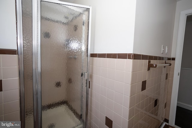 full bath featuring a stall shower and tile walls