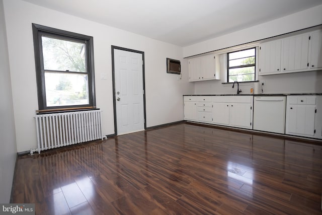 kitchen featuring radiator, dishwasher, dark countertops, dark wood-type flooring, and a sink