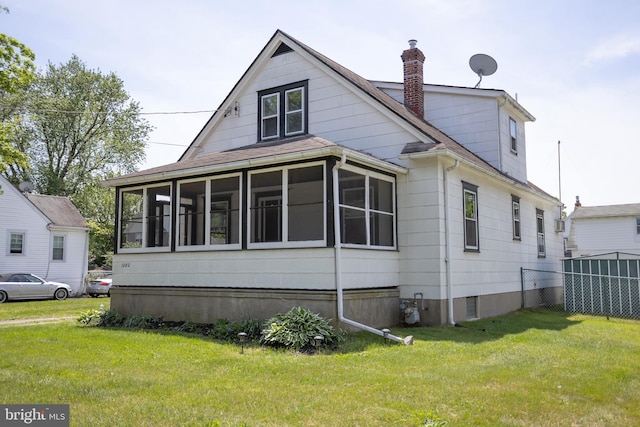 view of side of property with a chimney, a sunroom, and a shingled roof