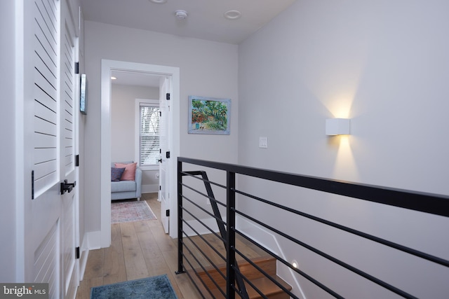 hallway with an upstairs landing, light wood-style flooring, and baseboards