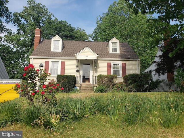 new england style home with a chimney, a shingled roof, and fence