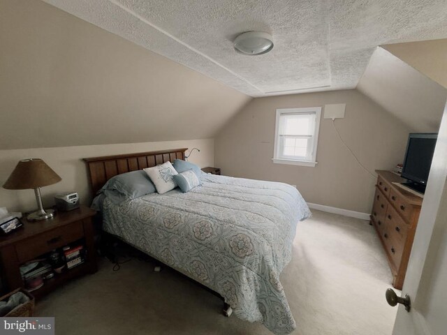 bedroom with light carpet, a textured ceiling, vaulted ceiling, and baseboards