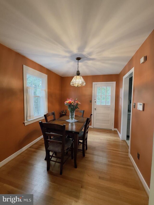 dining area with light wood-type flooring, baseboards, and a chandelier