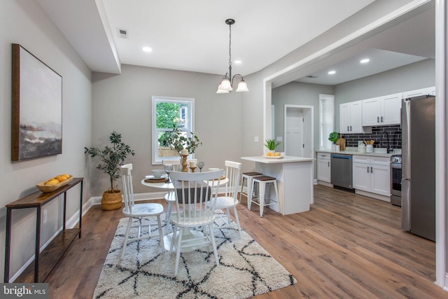 dining room with wood finished floors, baseboards, recessed lighting, and a chandelier