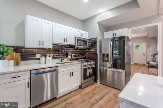 kitchen featuring stainless steel appliances, a sink, white cabinetry, and recessed lighting