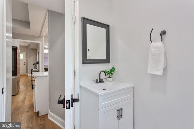 corridor featuring a sink, light wood finished floors, and baseboards