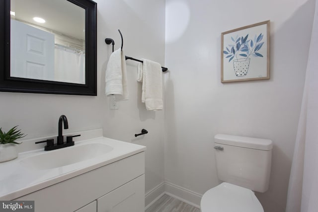 bathroom featuring toilet, vanity, and baseboards