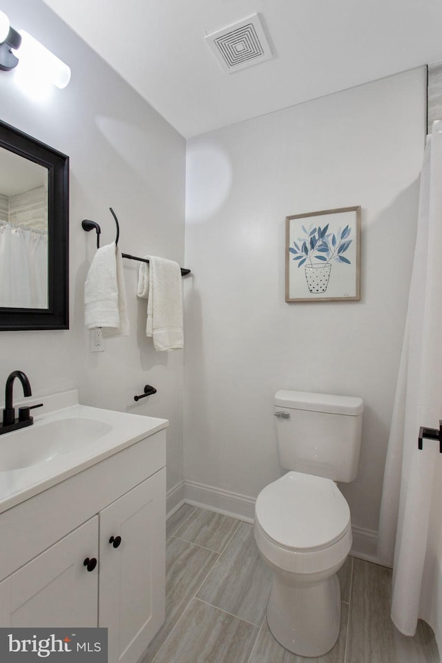full bath with baseboards, toilet, vanity, and wood finish floors