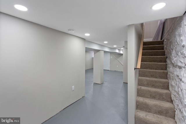 stairway featuring finished concrete flooring and recessed lighting