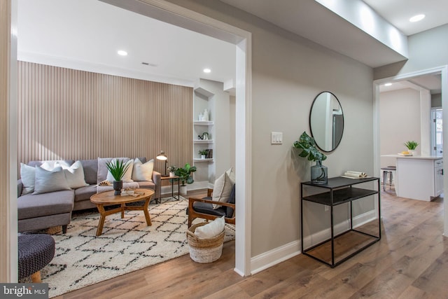 living room featuring wood finished floors, baseboards, recessed lighting, and built in features