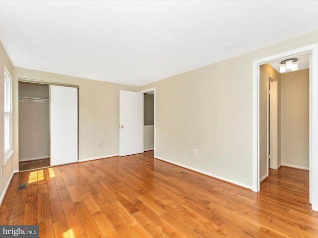unfurnished bedroom with light wood-type flooring, a closet, and baseboards