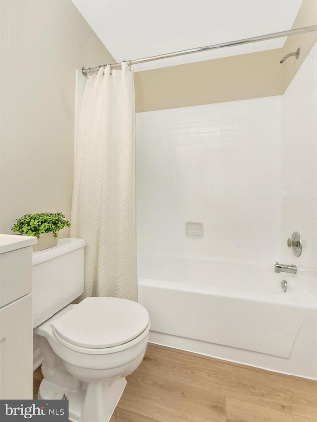 full bath with wood finished floors, toilet, shower / bath combo with shower curtain, and vanity