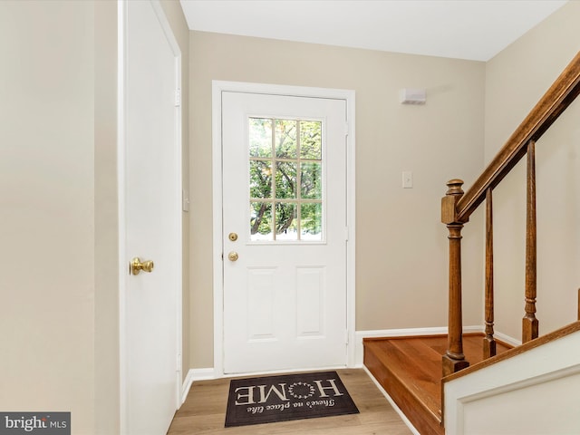 foyer entrance with stairs, wood finished floors, and baseboards